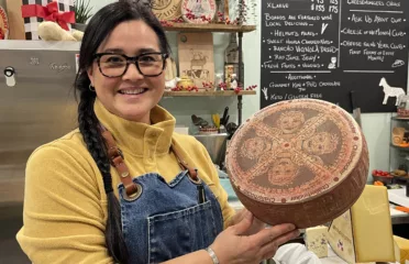 cheese shop keeper with cheese wheel