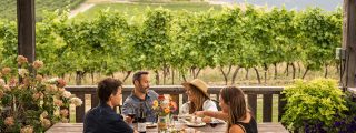 patio with food and wine and four people overlooking a vineyard in Creston BC